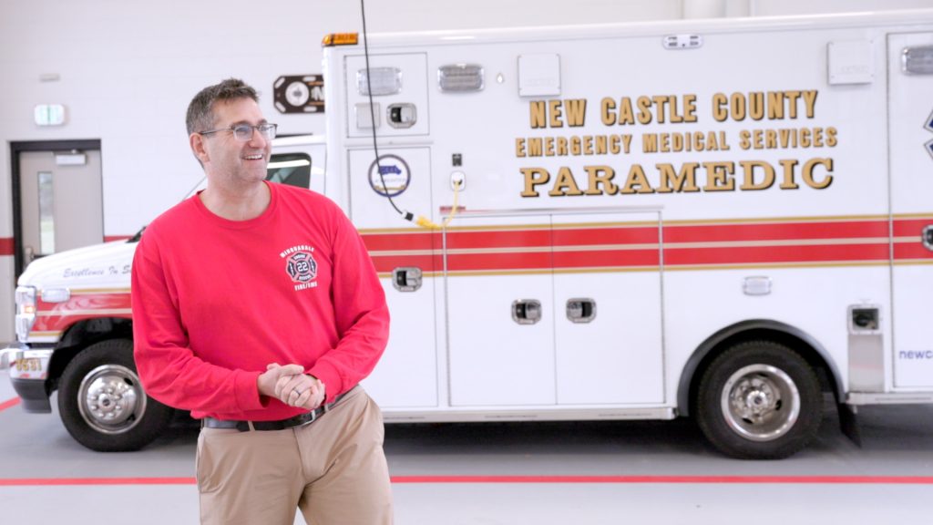 Governor Meyer standing with a New Castle County Paramedic emergency vehicle.